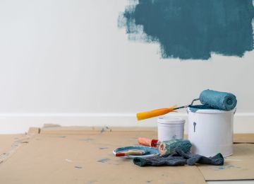 Close-Up Of Paint Roller On Container Against Wall